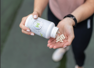 Woman holding supplement bottle pouring them into hand