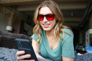 Woman wearing TrueDark Prescription Fairlane glasses with red lenses for ultimate blue light blockage